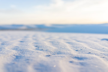 Macro closeup of sand in white sands dunes national monument in New Mexico showing texture on surface with mountains and hills in blurred background