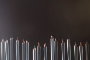 dark creative artistic background with sharpened colored pencils. Background for art workshops, artists' workshops, picture galleries, art schools or social advertising