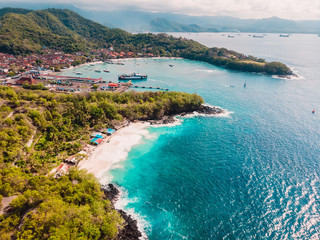 Fototapeta na wymiar Tropical beach and town in Bali with port, ferry and blue sea. Aerial view