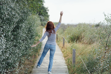 Carefree young woman dancing along a boardwalk