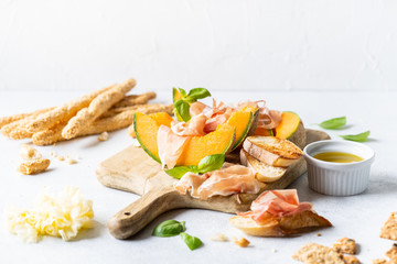 Fresh melon with prosciutto and basil. Antipasti, Italian food. Top view on white stone table with copy space for your text