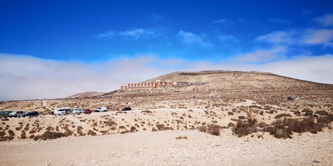 Hüglige Wüstenlandschaft an der Küste mit blauem Himmel