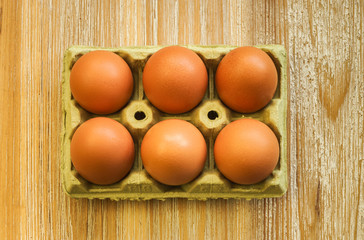 Still life with half a dozen organic eggs on a wooden board in light tones and rustic texture.