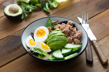 Healthy tuna and egg salad with avocado and fresh green salad mix leaves.