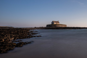 Fototapeta na wymiar Church In The Sea, Porth Cwyfan, Anglesey in the dramatic landscapes of scenic Wales, fantastic adventure travel destination or holiday vacation to view picturesque scenery at sunrise or sunset