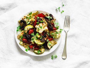 Roasted vegetables cauliflower, zucchini, mushrooms, peppers on a light background, top view. Vegetarian food