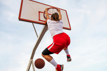 Females playing basketball on street court. Woman streetball player making slam dunk in a basketball game. © FS-Stock