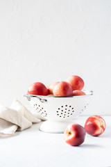 Naklejka na ściany i meble Fresh peaches and nectarines for a delicious Breakfast in a white iron bowl on a white background. The concept of delicious and healthy food. Copy space.