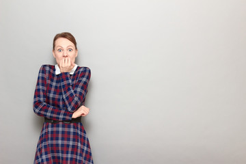 Portrait of shocked frightened girl biting her nails in panic