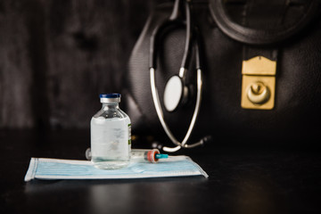 Health care black vintage doctor's medical bag with a stethoscope for a physician to use at work or home calls with stethoscope, medicine, protective face mask and a syringe