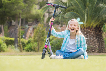 Active little girl with scooter  in park outdoors on summer day.  Summer time fun