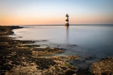 Fototapeta premium Penmon Point Lighthouse, Beaumaris Anglesey in the dramatic landscapes of scenic Wales, fantastic adventure travel destination or holiday vacation to view picturesque scenery at sunrise or sunset