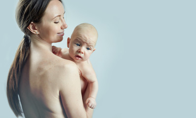 Woman with a baby in her arms on a background of blue wall