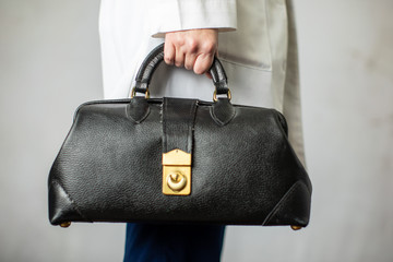 Female physician holding a black leather doctor's bag heading to the office to practice medicine