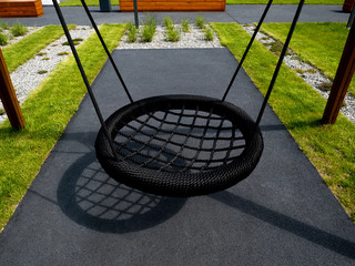 Modern new children's swing close up, isolated, at the playground of the residential complex.