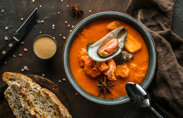 Tomato gazpacho soup with mussels, squid, shrimp in bowl over dark wooden background with napkin. Seafood, healthy food, top view