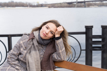 Smiling beautiful girl in a park in a fashionable coat. Checkered autumn coat