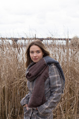Naklejka na ściany i meble Smiling beautiful girl in a park in a fashionable coat. Checkered autumn coat