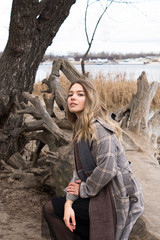 Smiling beautiful girl in a park in a fashionable coat. Checkered autumn coat