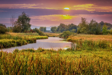 Fototapeta na wymiar Sunset over the river. Picturesque autumn landscape with river and colorful clouds at sunset
