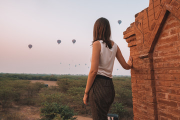 Woman watches balloons over temples in Bagan, Myanmar