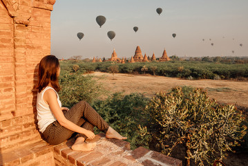 Woman looking baloons over the temples at sunrise in Bagan, Myanmar
