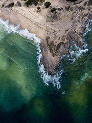 Uruguay, Punta del diablo. Aerial view of the beach and the sea. The waves crash against the sand and rocks, the water is green and dark.
Uruguay has these wild and lonely beaches.