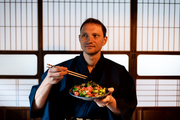 Traditional japanese house or ryokan restaurant with tourist man in kimono or yukata eating from...