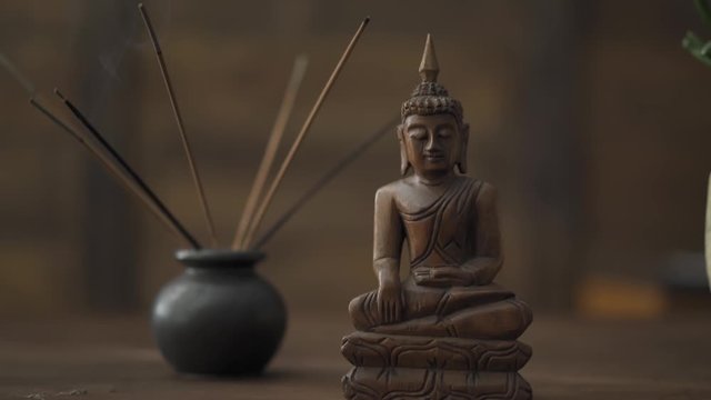 Buddha statuette and incense bowl, decorative paraphernalia on the table of a freelancer. Work during the quarantine period of the coronavirus pandemic. Prores 422.