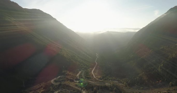 Sunrise just over mountain tops with road travelling up valley