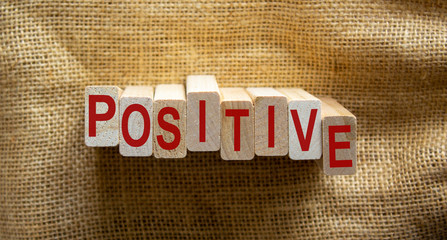 Wooden block form the text 'positive' on beautiful canvas background.