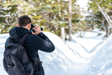 Takayama, Japan and back of man taking picture of snow covered trail in Shinhotaka Ropeway in Gifu Prefecture mountain park with trees