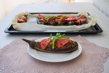 Traditional Turkish food eggplant stuffed / filled with minced meat, tomato, pepper on plate. This food as known Karniyarik or Imam Bayildi. Popular Turkish or Greek fresh food on white background.