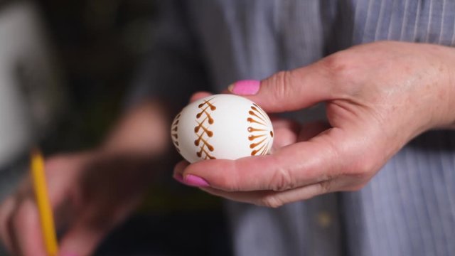Woman paint Easter eggs in an authentic way with wax candles and paint. Home Easter holiday leisure