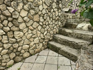 The stone wall of an Orthodox monastery. Green plants, Stone steps.