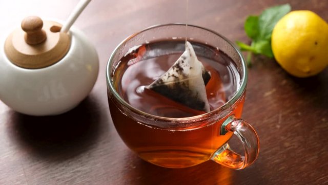 Black tea using tea bag in glass cup on wooden table