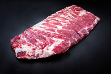 Raw veal spare loin ribs St Louis cut offered as top view on black background