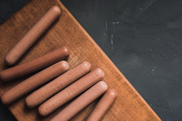 Sausages on a beautiful background for advertising on a wooden board. grey matte concrete background. 
