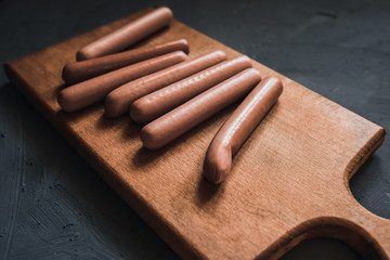 Sausages on a beautiful background for advertising on a wooden board. grey matte concrete background. 
