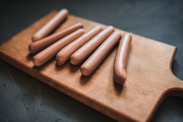 Sausages on a beautiful background for advertising on a wooden board. grey matte concrete background. 
