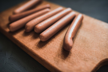 Sausages on a beautiful background for advertising on a wooden board. grey matte concrete background. 