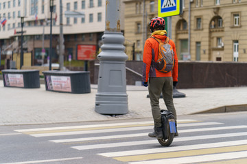 Young man driving Electric unicycle in the city center. He know how to be fast in the city. Coronavirus pandemic time. No people at the street.  No traffic. Man crossing the pedestrian crosswalk