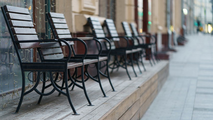 Empty wooden benches near closed cafe at Sretenka street in the Moscow city center. Coronsvirus pandemic. Beautiful sunset in the city without people. Spring evening.