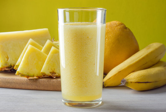 A Glass Of Fresh Banana, Pineapple, Orange Smoothie On White Table