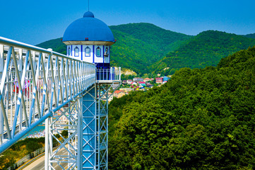 Beautiful white bridge for the descent to the sea against the background of green mountains