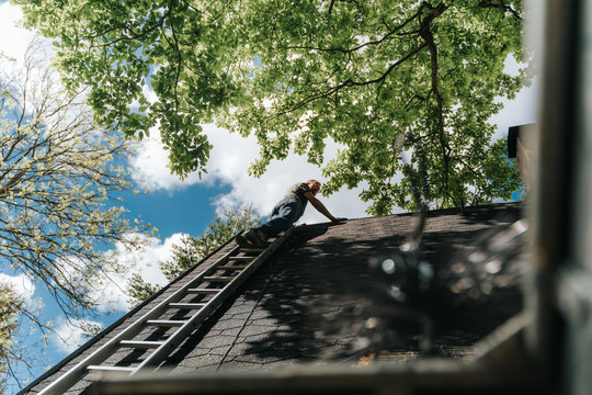 home owner climbing up rooftop on ladder