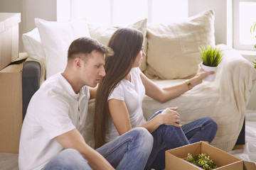 Portrait of happy couple looking at laptop computer together sitting in new house, surrounded with boxes