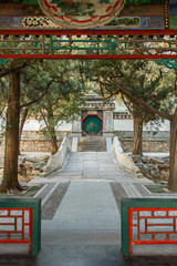 Alley in the imperial garden, path leading through a small bridge to the decorated gate.