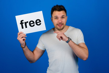Handsome stylish man standing with a sign in his hand in the studio on a blue background. Cool.
