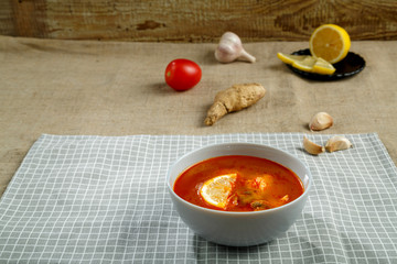 Tom yum soup with chicken in a plate on a tablecloth on a linen napkin. Horizontal photo
